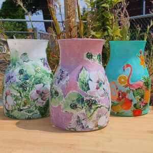 Deelnemer bewerkt een vaas met decoupage tijdens een creatieve workshop, gebruikmakend van servetten en acrylverf.